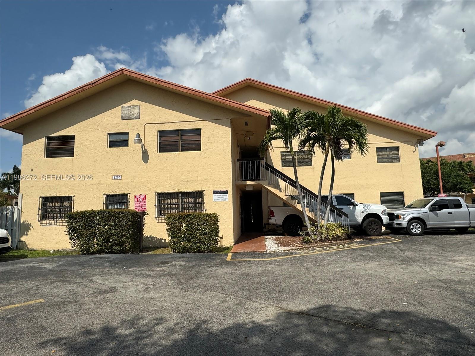 A two-story yellow apartment building features an exterior staircase and a parking lot — 2295 W 53rd Pl # 201, Hialeah FL 33016, HIALEAH, FL