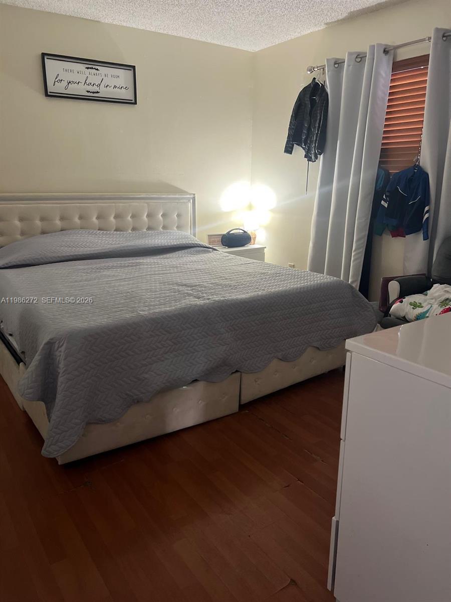 A bedroom features a tufted headboard bed, wood-look flooring, and a wall-mounted sign — 2295 W 53rd Pl # 201, Hialeah FL 33016, HIALEAH, FL