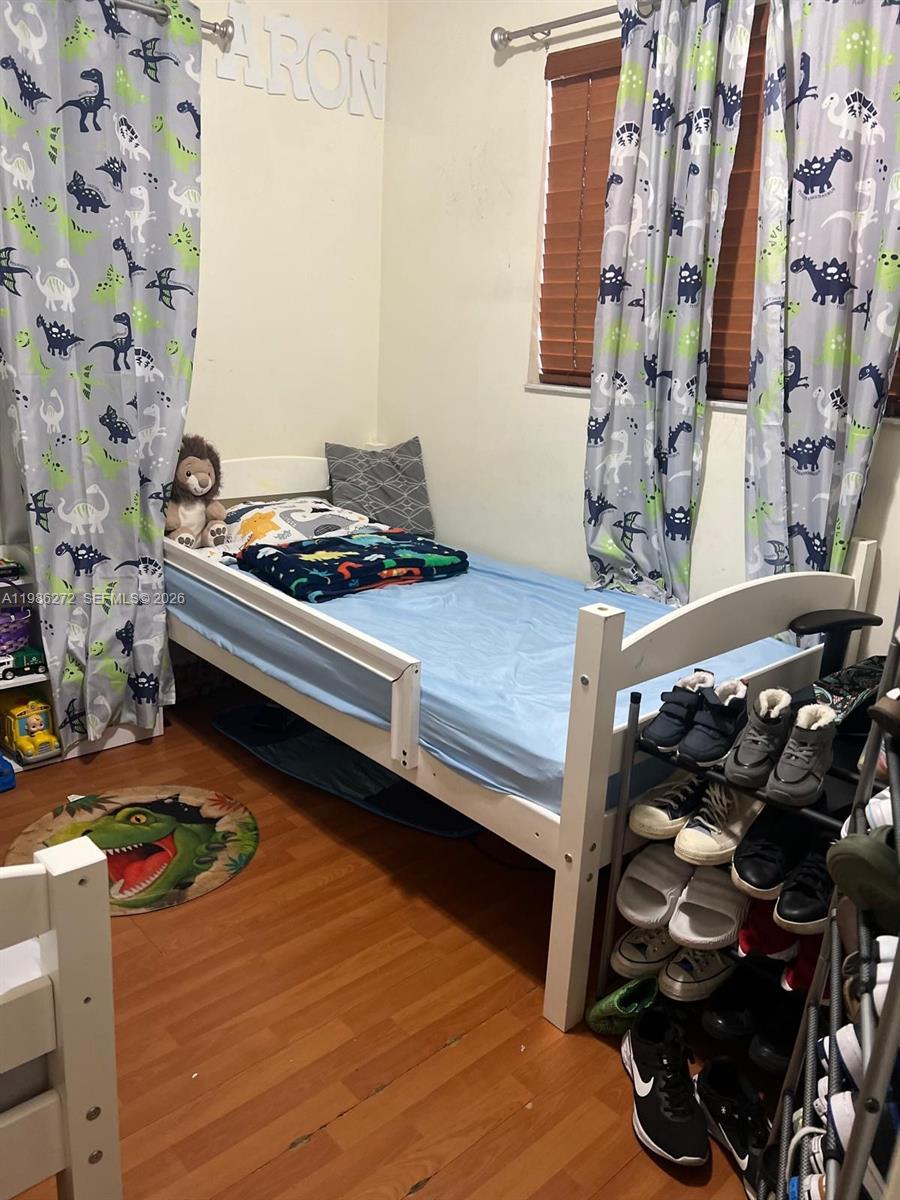 A child's bedroom features a twin bed, dinosaur-themed curtains, and a shoe rack — 2295 W 53rd Pl # 201, Hialeah FL 33016, HIALEAH, FL