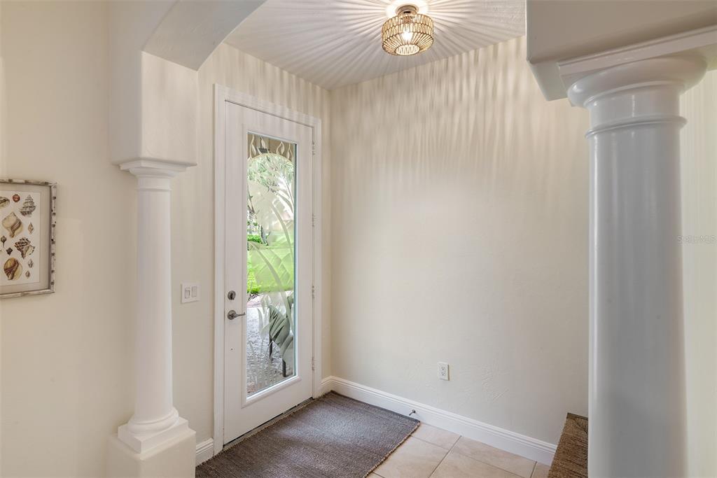 An entryway features a white door with glass panels, a decorative light fixture, and columns — 120 AVENUE DE LA MER UNIT 1501, PALM COAST, FL