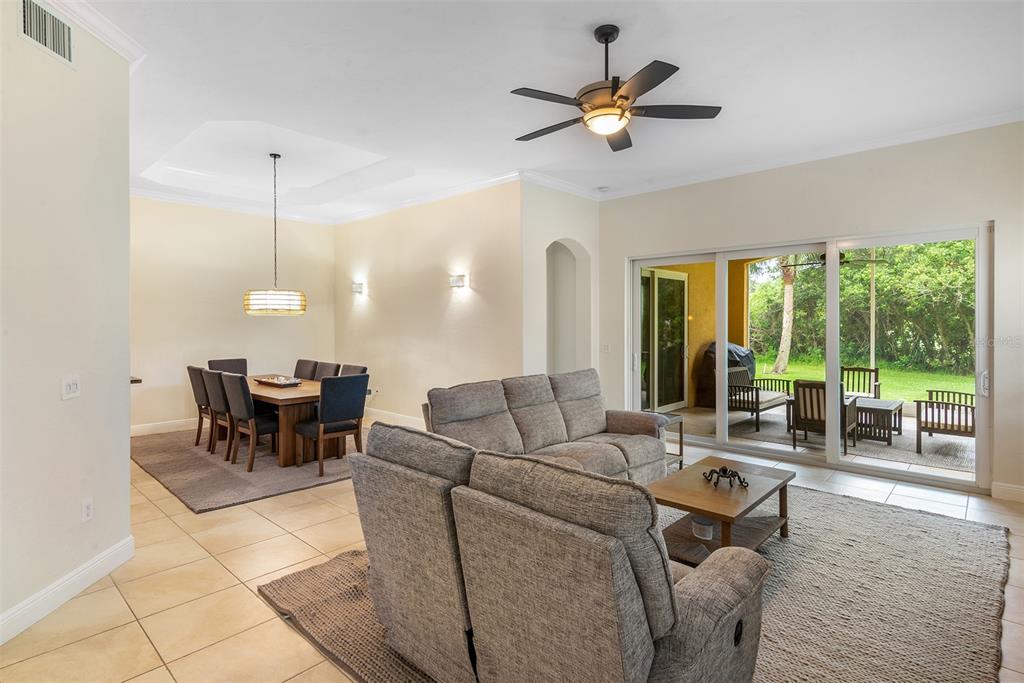 A living room and dining area with tile floors, neutral walls, and sliding glass doors — 120 AVENUE DE LA MER UNIT 1501, PALM COAST, FL