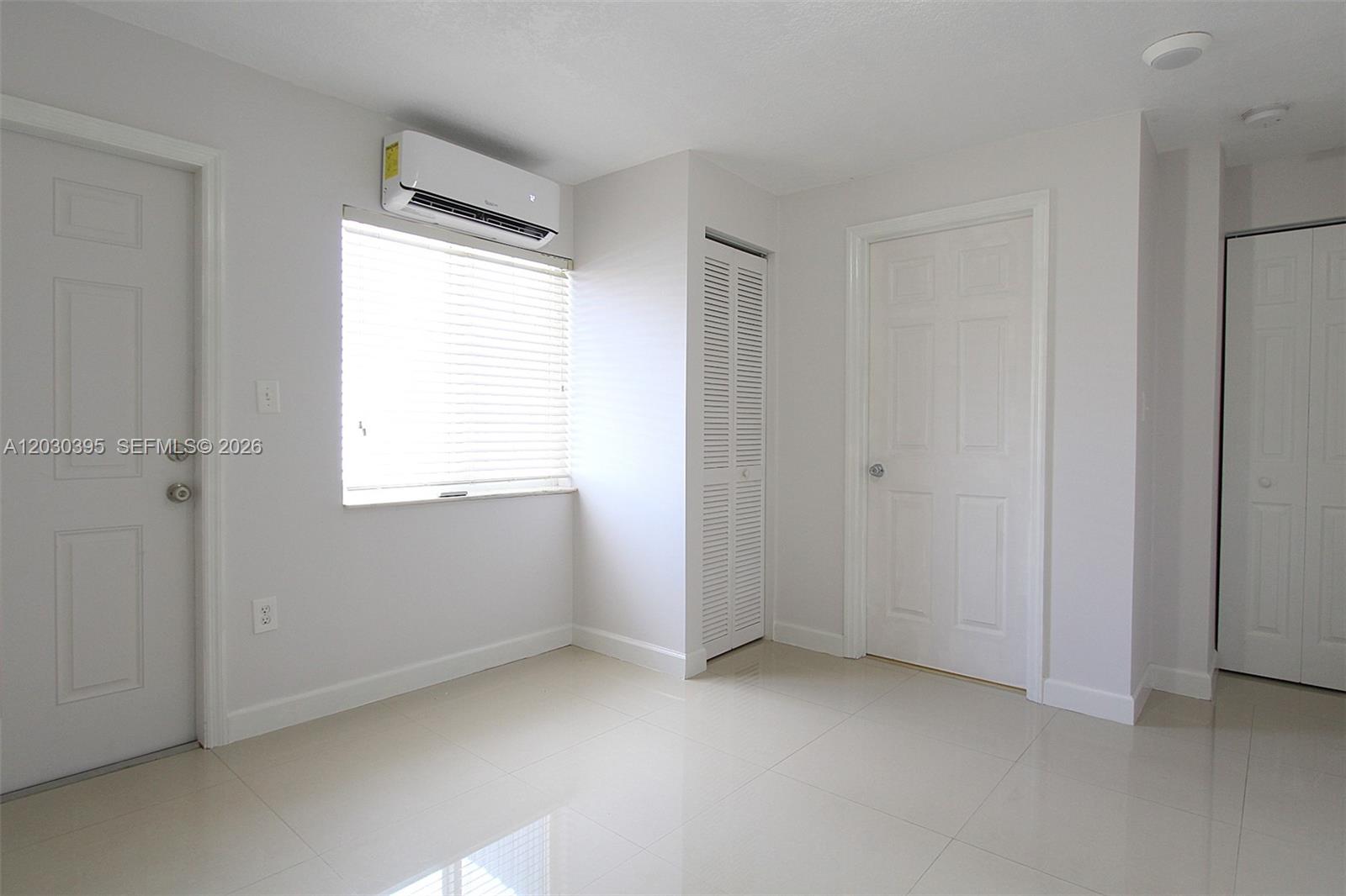 A bright, empty room features white walls, tiled floors, a window, and several white doors — 7281 SW 9th St # 2, Miami FL 33144, MIAMI, FL