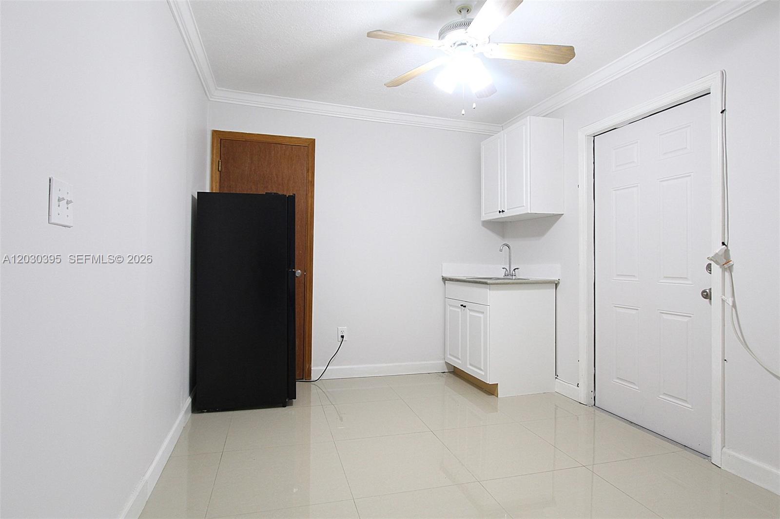 A small kitchen area features white cabinets, a sink, a black refrigerator, and tile flooring — 7281 SW 9th St # 2, Miami FL 33144, MIAMI, FL