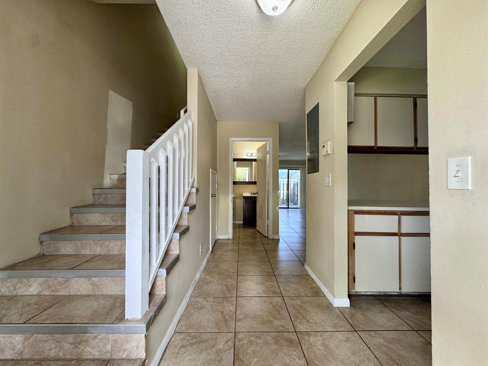 A tiled hallway leads to a bathroom and living area, with stairs on the left — 704 Riverside Drive, FL 33463, FL