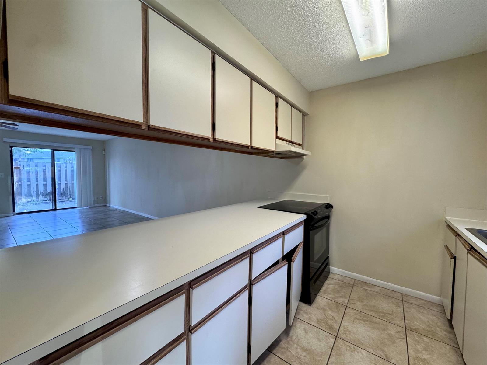 A kitchen features white cabinets with wood trim, a black stove, and beige tile flooring — 704 Riverside Drive, FL 33463, FL