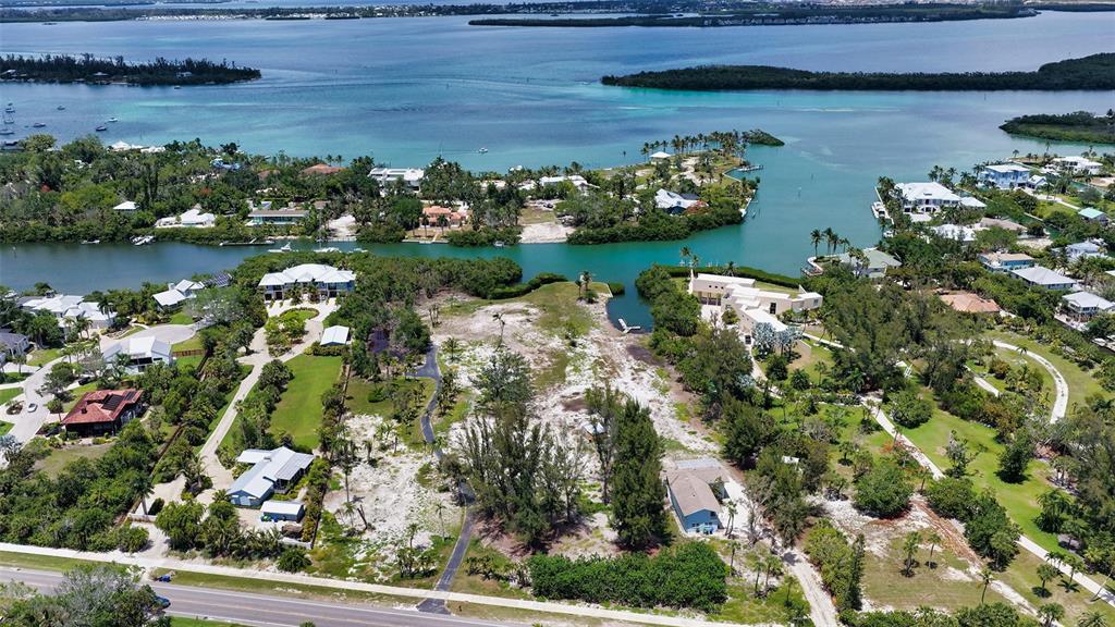 An aerial view shows a large, partially cleared waterfront lot surrounded by trees and houses — 6660 & 6664 & 6670 GULF OF MEXICO DRIVE, LONGBOAT KEY, FL
