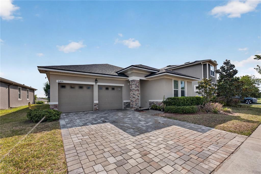 A single-story house with a two-car garage, stone accents, and a paved driveway — 16466 OLIVE HILL DRIVE, WINTER GARDEN, FL