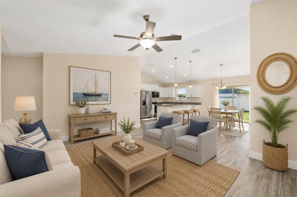 An open-concept living room and kitchen featuring light wood furniture, neutral walls, and striped chairs — 93 PECAN PASS, OCALA, FL