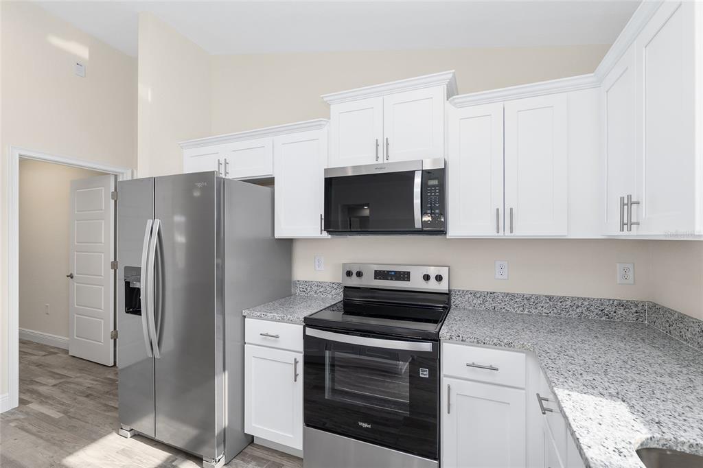 A kitchen with white cabinets, granite countertops, and stainless steel appliances — 93 PECAN PASS, OCALA, FL