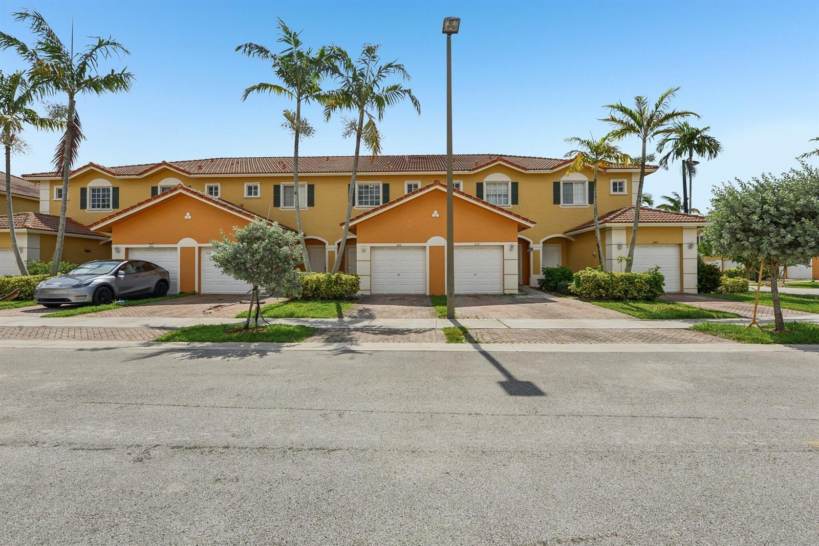 A row of two-story townhomes with orange stucco facades, tiled roofs, and attached garages — 560 St Tropez Lane, Margate FL 33068, MARGATE, FL