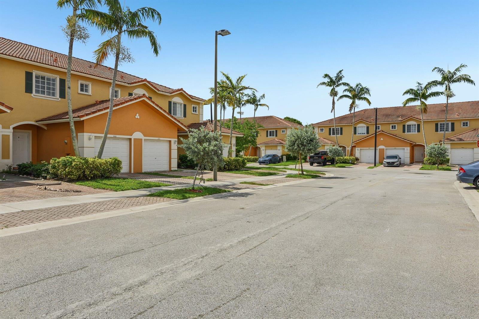 A street view of two-story townhouses with orange stucco walls and palm trees — 560 St Tropez Lane, Margate FL 33068, MARGATE, FL