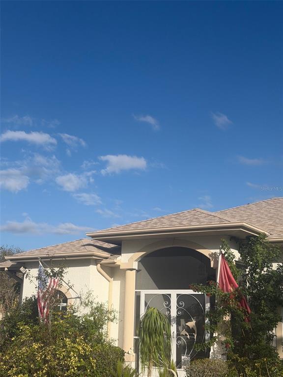 The exterior of a house features a tan roof, a screened entryway, and two flags — 3816 N CRANBERRY BOULEVARD, NORTH PORT, FL