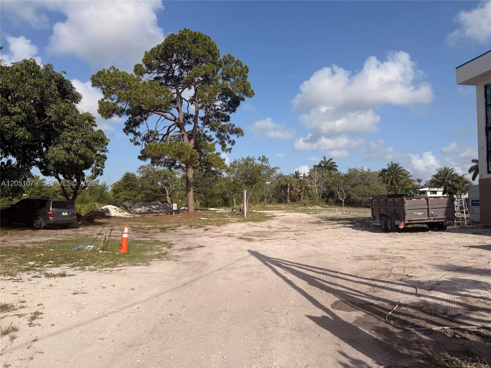 A dirt lot features a large pine tree, a parked SUV, and a utility trailer — 1417 Florian Dr, Dania Beach FL 33004, DANIA BEACH, FL