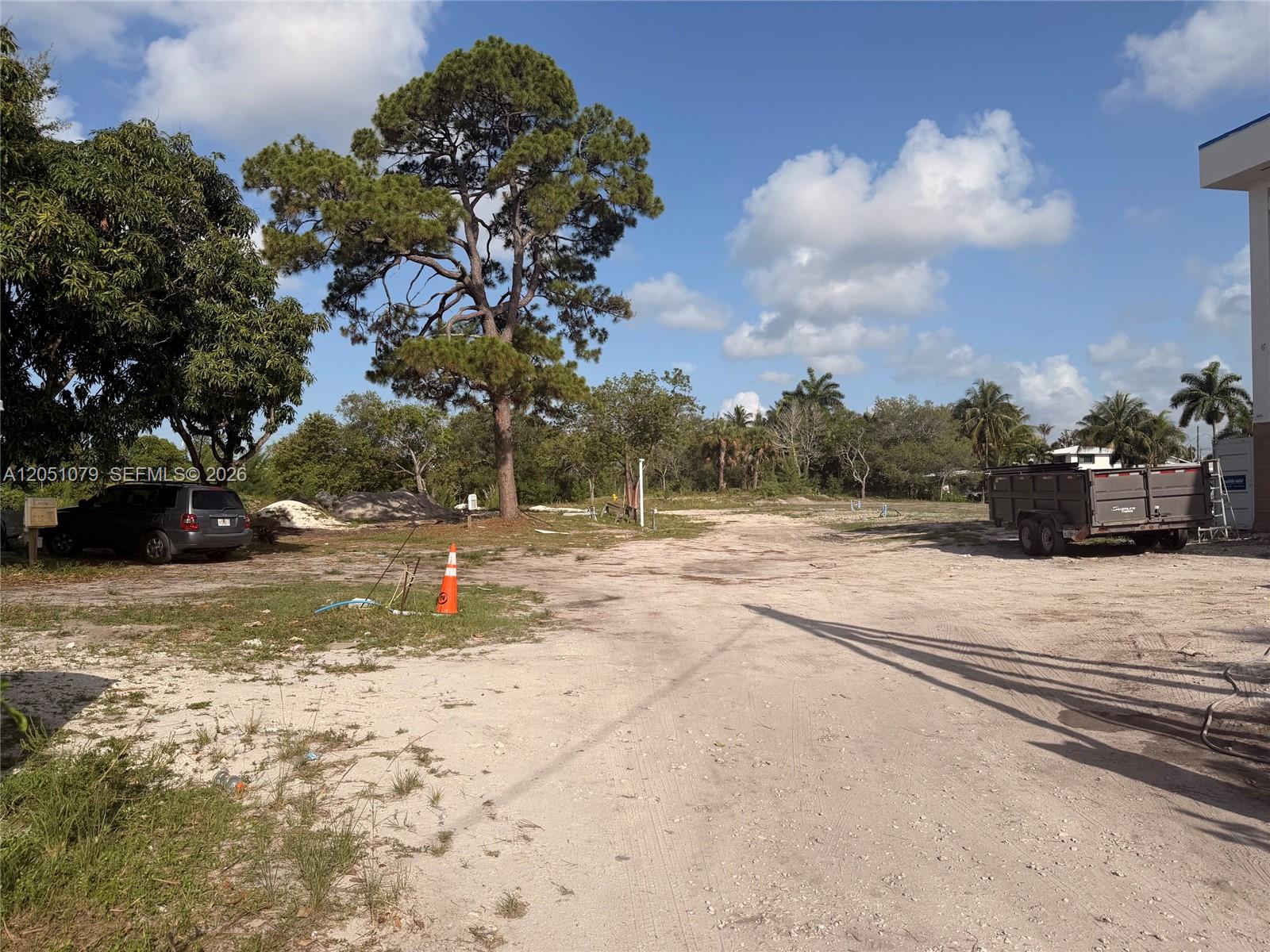 A large, unpaved dirt lot features a tall pine tree, a parked SUV, and a trailer — 1417 Florian Dr, Dania Beach FL 33004, DANIA BEACH, FL