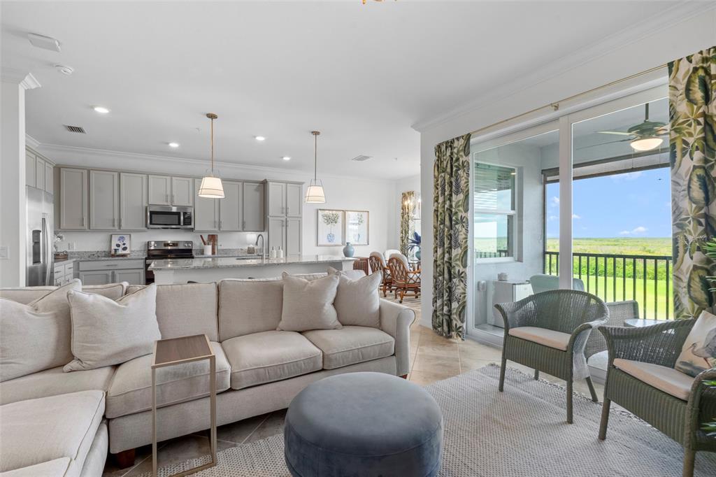 An open-concept living room and kitchen with light cabinetry, neutral furniture, and a balcony view — 14061 HERITAGE LANDING BOULEVARD UNIT 445, PUNTA GORDA, FL