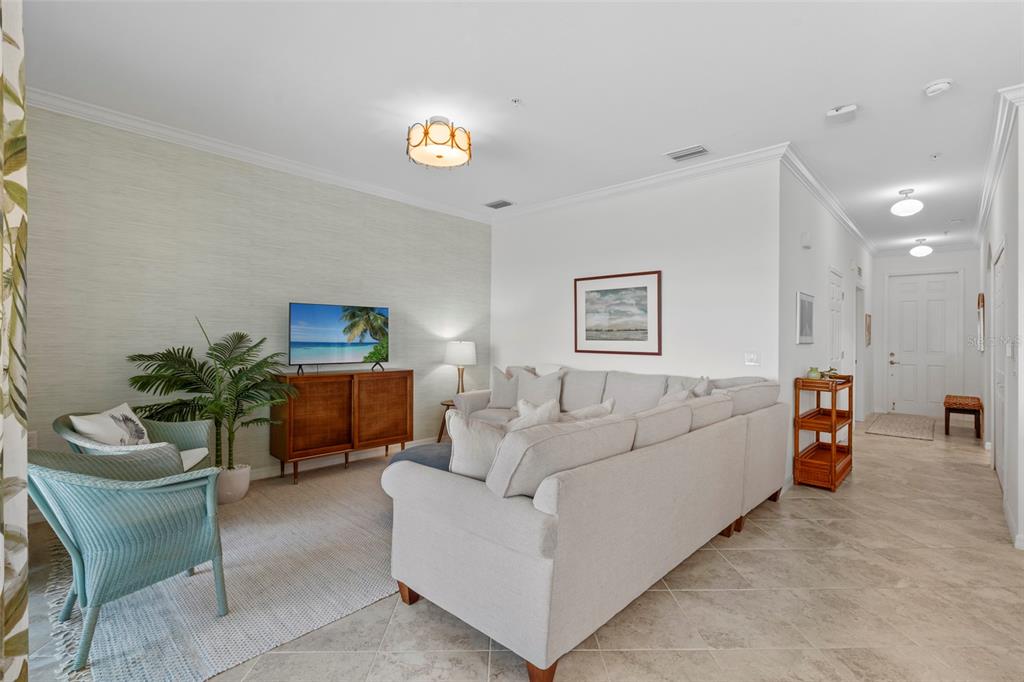 A living room features a sectional sofa, two wicker chairs, a television, and tile flooring — 14061 HERITAGE LANDING BOULEVARD UNIT 445, PUNTA GORDA, FL