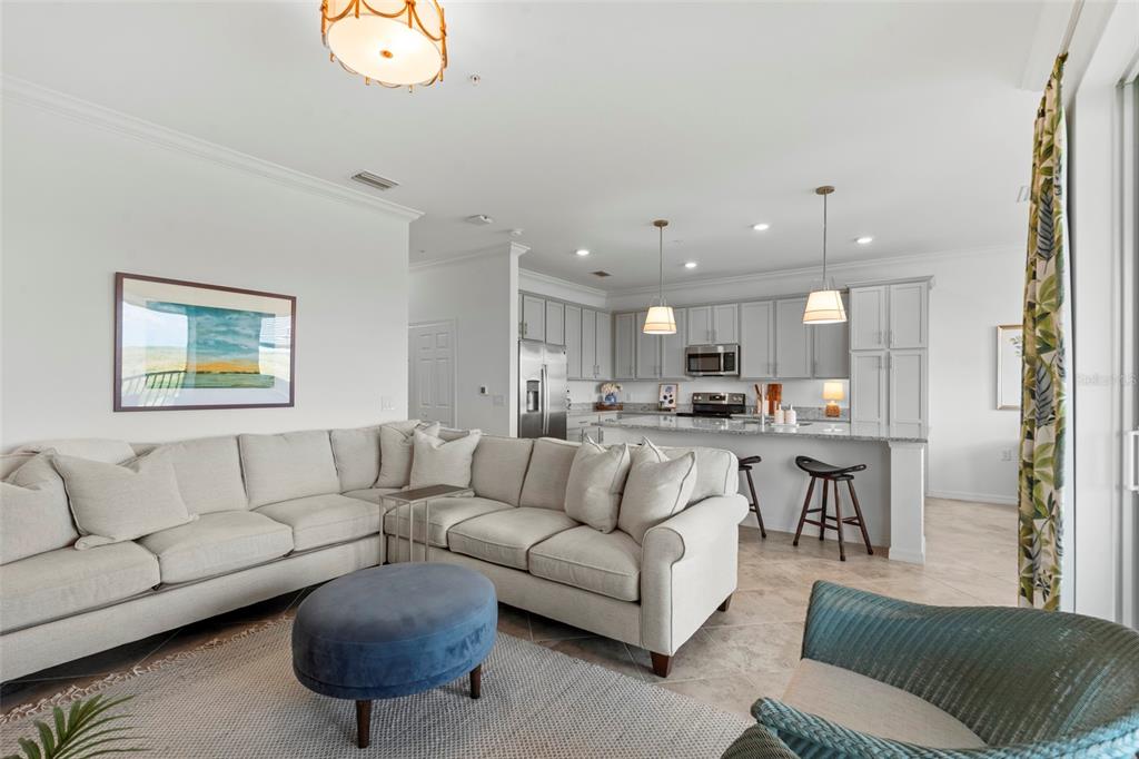 An open-concept living room and kitchen featuring a sectional sofa, kitchen island, and pendant lighting — 14061 HERITAGE LANDING BOULEVARD UNIT 445, PUNTA GORDA, FL