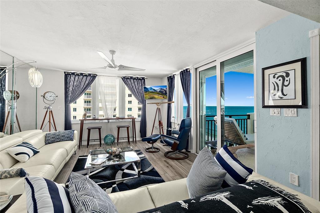 A living room with white leather sofas, a glass coffee table, and a balcony view — 2947 S ATLANTIC AVENUE UNIT 1604, DAYTONA BEACH, FL