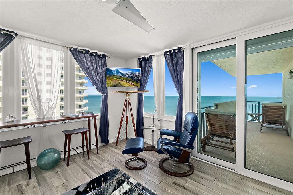 A sunroom with a blue leather recliner, a telescope, and a balcony overlooking the ocean — 2947 S ATLANTIC AVENUE UNIT 1604, DAYTONA BEACH, FL