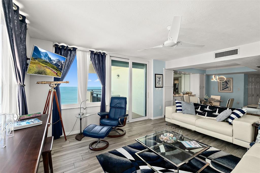 A living room with a white sofa, blue recliner, glass coffee table, and ocean view — 2947 S ATLANTIC AVENUE UNIT 1604, DAYTONA BEACH, FL