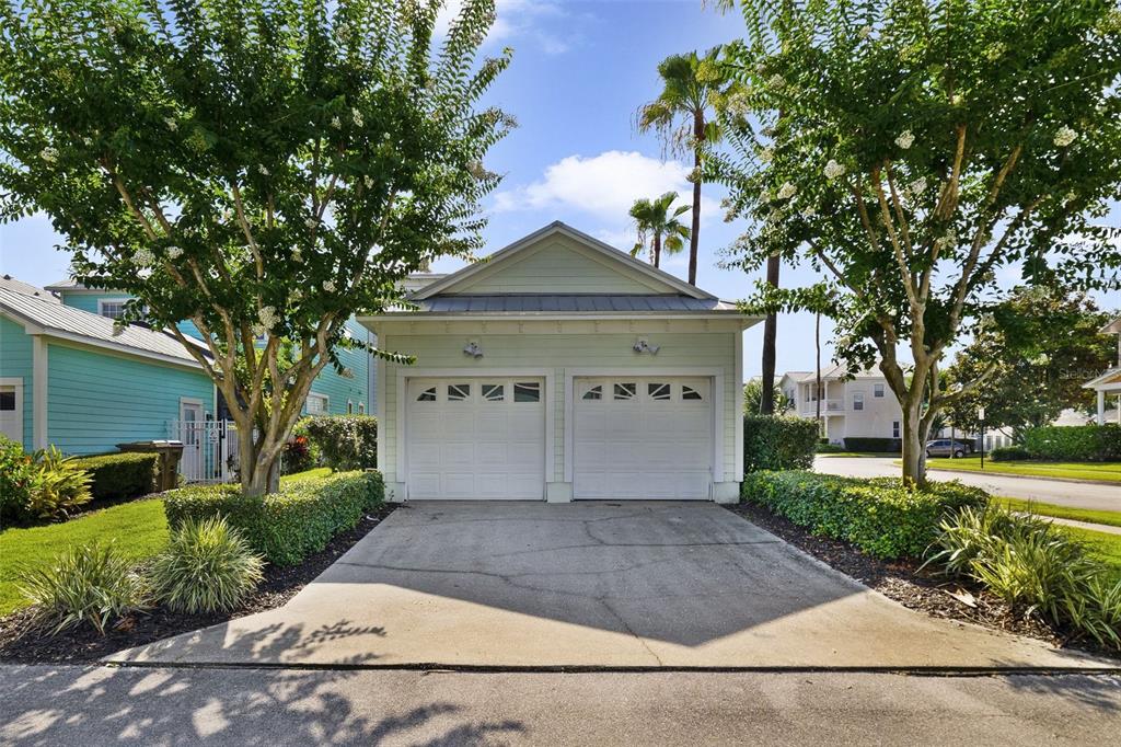 A detached two-car garage with light green siding and white doors sits between two trees — 7740 LINKSIDE LOOP UNIT 7740, KISSIMMEE, FL
