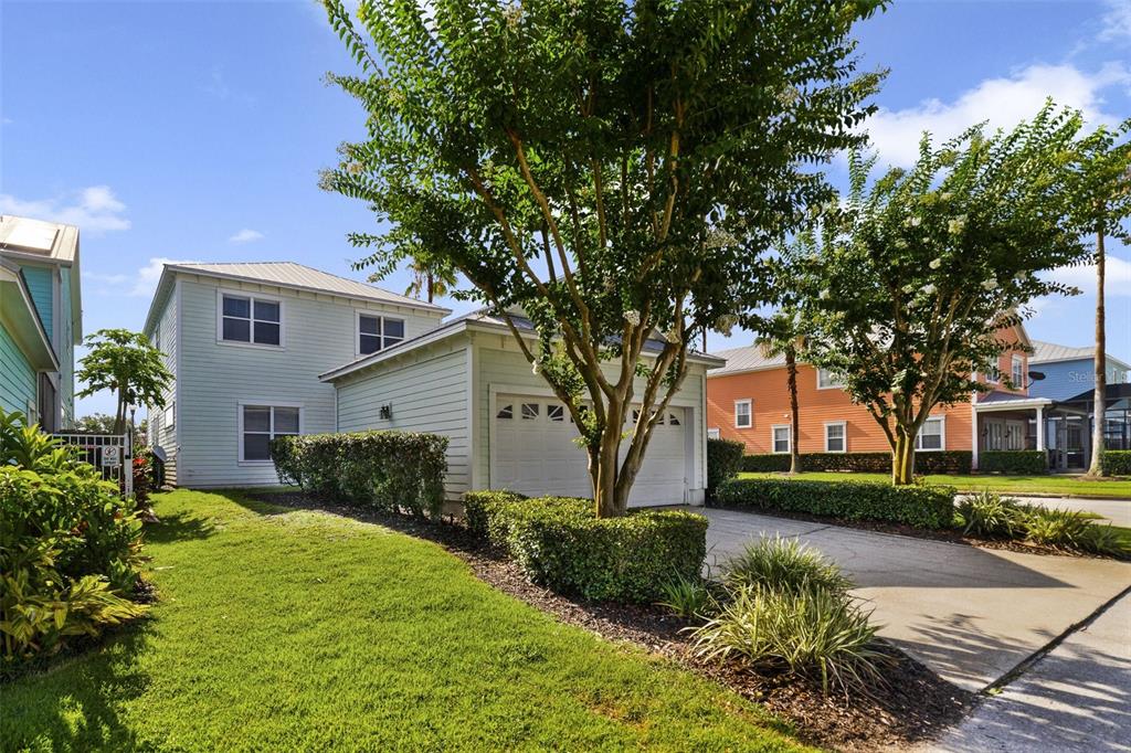 A light blue two-story house with a garage, driveway, and manicured landscaping — 7740 LINKSIDE LOOP UNIT 7740, KISSIMMEE, FL