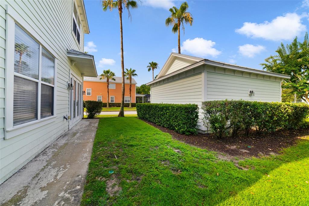 A side view of a house with a concrete walkway, green lawn, and detached garage — 7740 LINKSIDE LOOP UNIT 7740, KISSIMMEE, FL