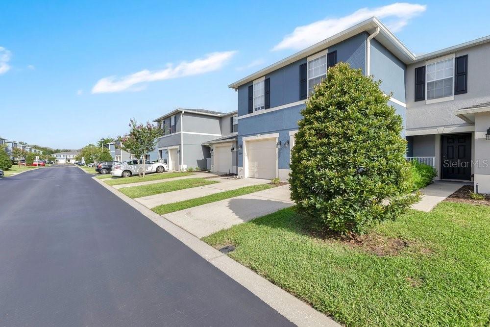 A two-story townhouse with a blue exterior, a garage, and a large front shrub — 12640 SOMERSET OAKS STREET, ORLANDO, FL