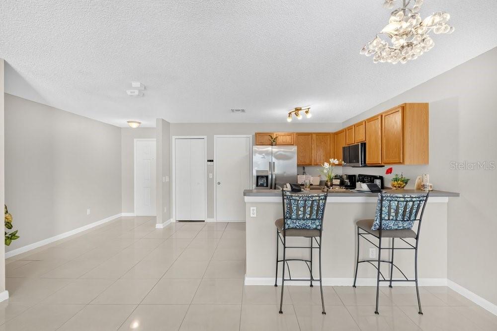 A kitchen with wood cabinets and a breakfast bar overlooks an open-concept living area — 12640 SOMERSET OAKS STREET, ORLANDO, FL