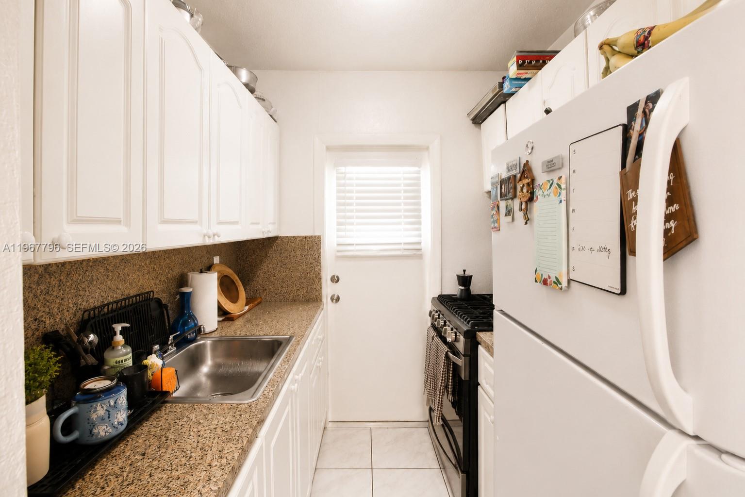 A kitchen features a gas stove, a light blue microwave, and a black air fryer — 3901 SW 78th Ct # 116, Miami FL 33155, MIAMI, FL