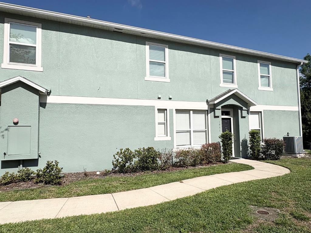A two-story light green stucco townhouse with a walkway leading to the front entrance — 1931 SAN JACINTO CIRCLE UNIT 1931, SANFORD, FL