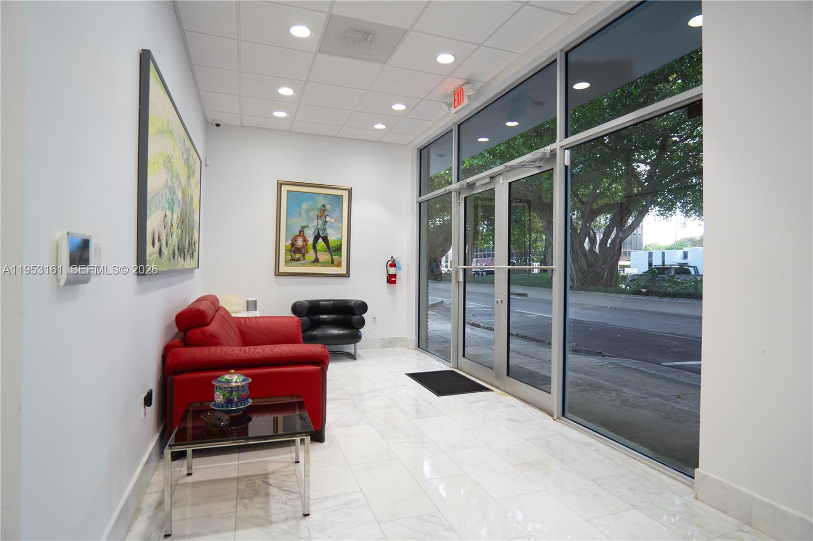 A waiting area features a red sofa, black chair, marble floors, and floor-to-ceiling glass doors — 1875 SW 22nd St, Miami FL 33145, MIAMI, FL