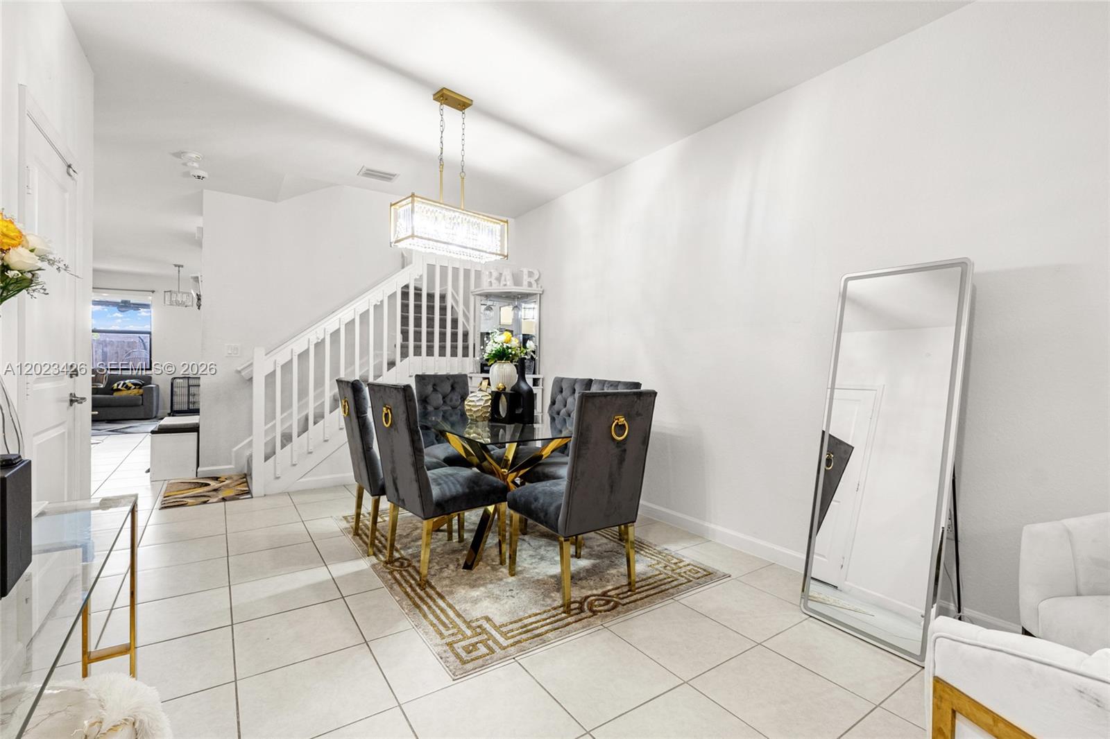 A dining area features a glass table, velvet chairs, a crystal chandelier, and a floor mirror — 23021 SW 128th Pl, Miami FL 33170, MIAMI, FL
