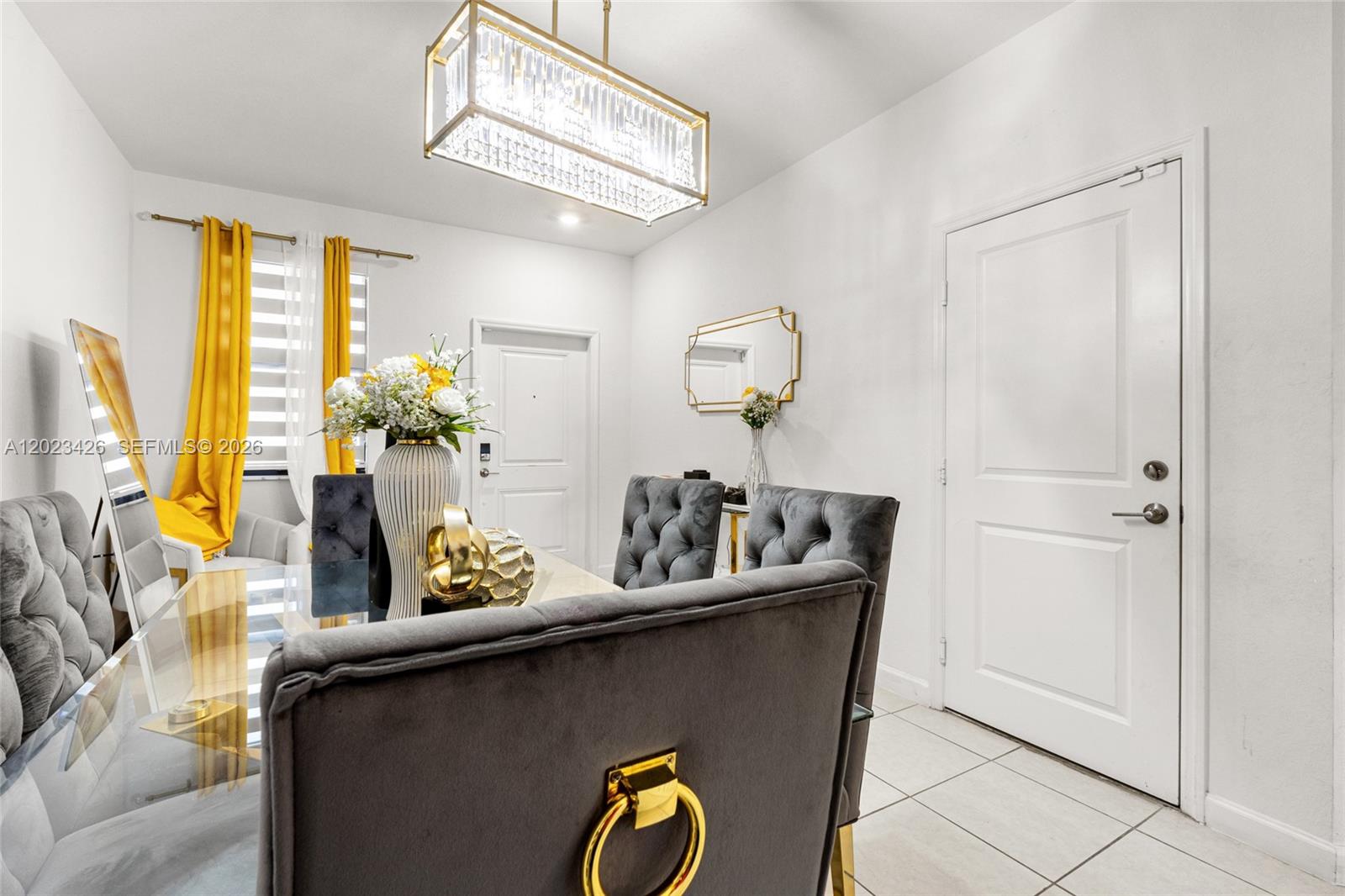A dining room features a glass table, grey tufted chairs, and a crystal chandelier — 23021 SW 128th Pl, Miami FL 33170, MIAMI, FL