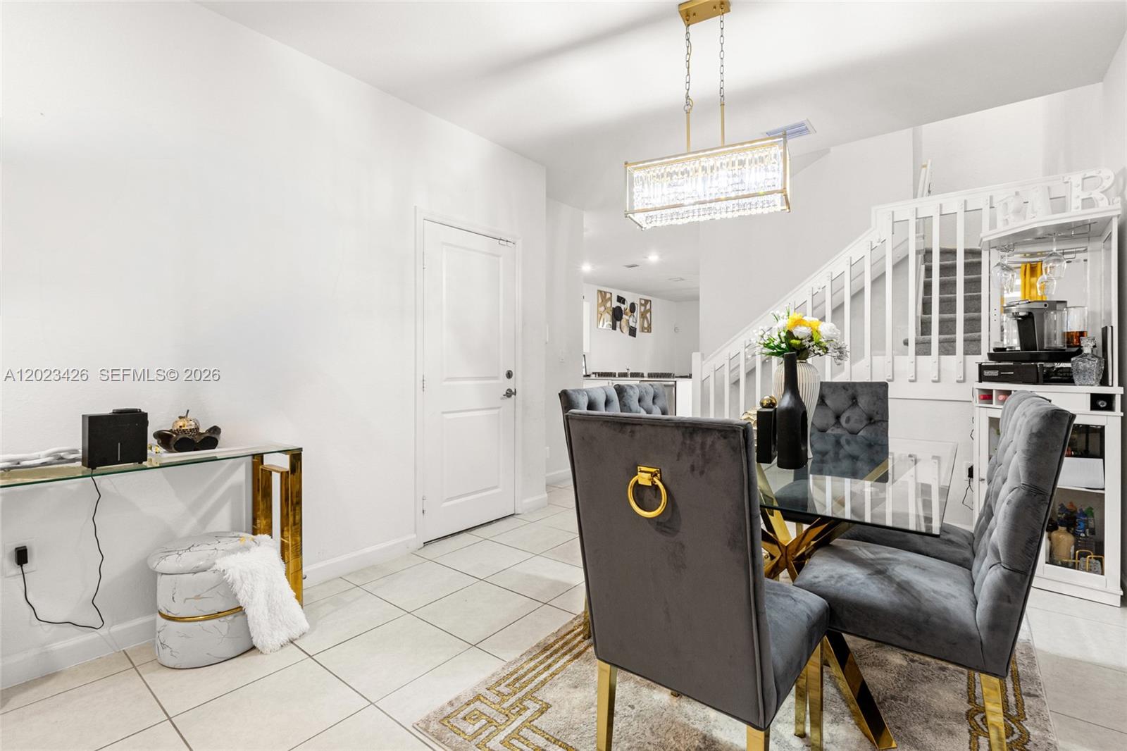 A dining area features a glass table, grey tufted chairs, and a crystal chandelier — 23021 SW 128th Pl, Miami FL 33170, MIAMI, FL