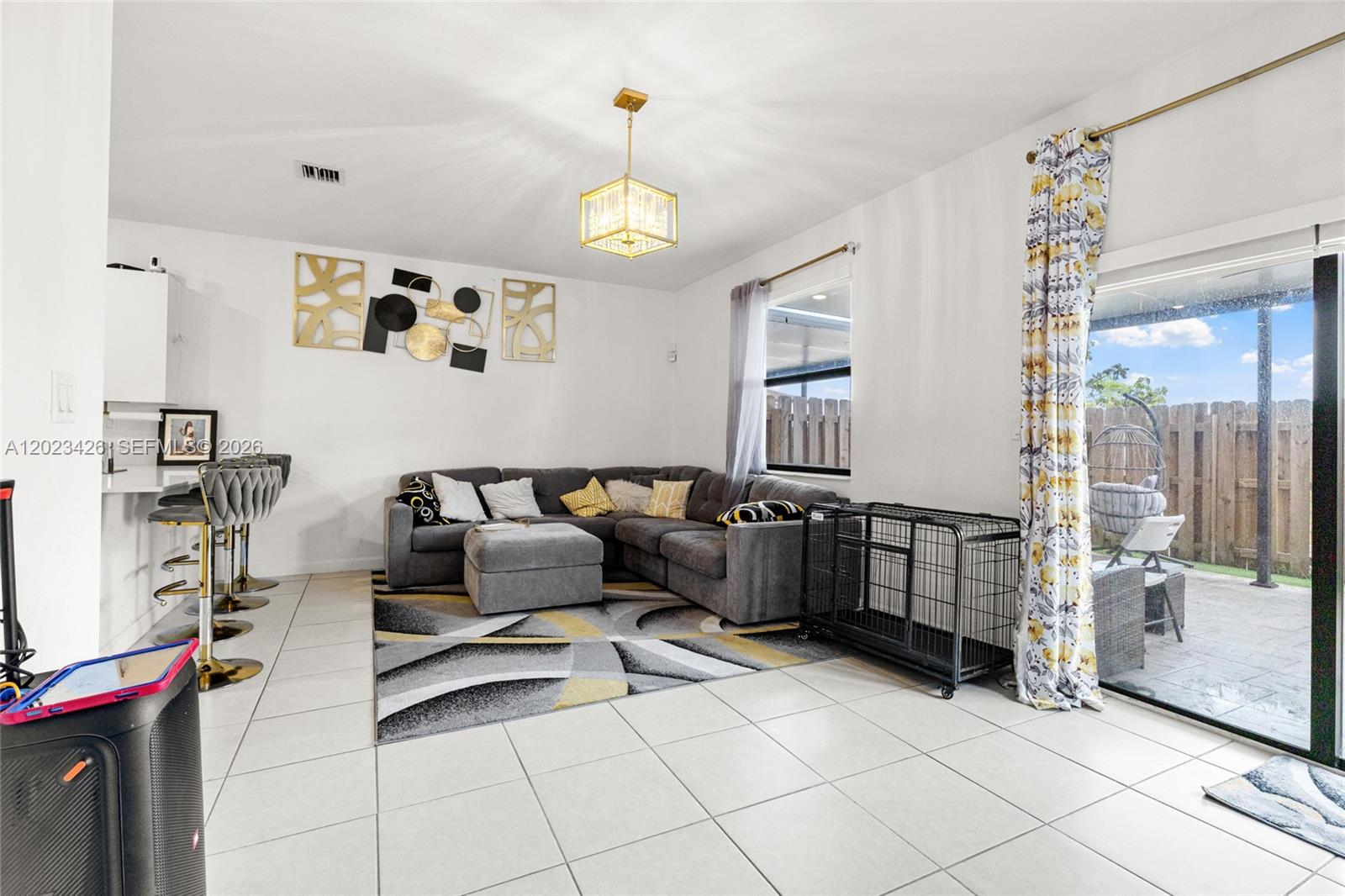 A living room features a grey sectional sofa, a patterned area rug, and a sliding door — 23021 SW 128th Pl, Miami FL 33170, MIAMI, FL