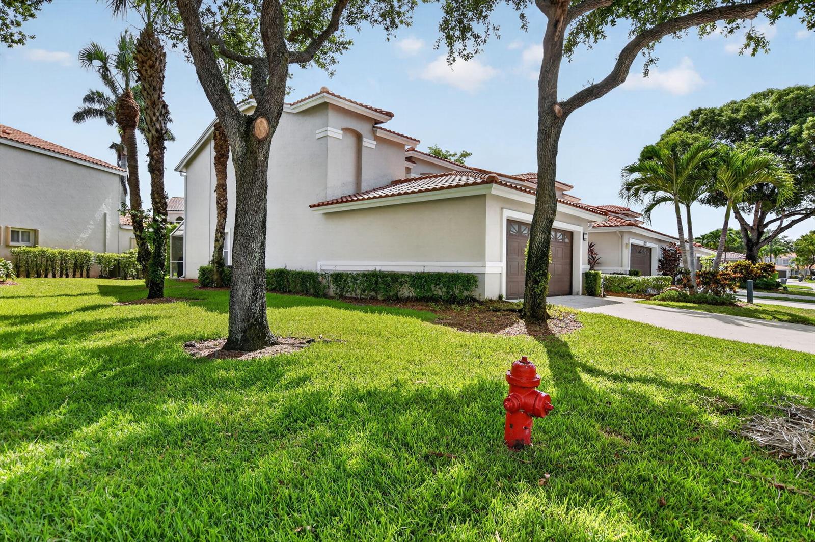 A red fire hydrant sits on a grassy lawn in front of a suburban townhouse — 10401 Lake Vista Circle, Boca Raton FL 33498, BOCA RATON, FL