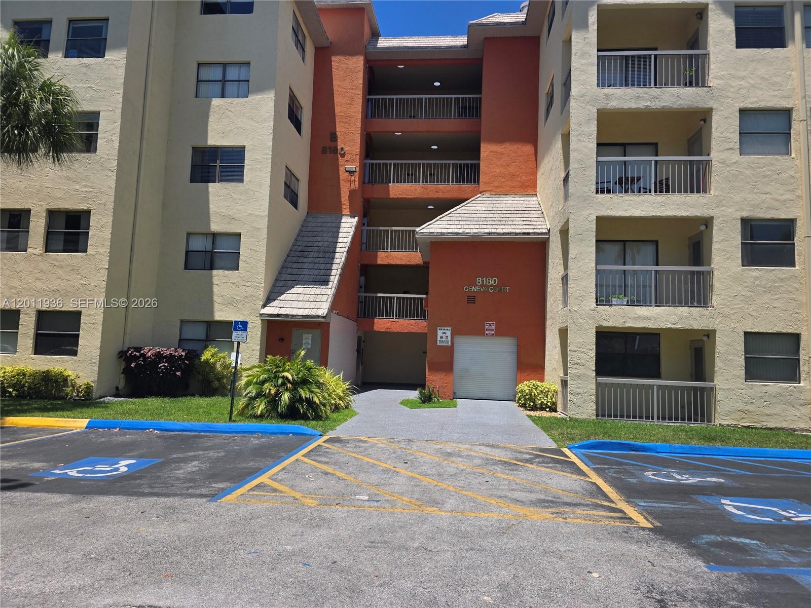 The exterior of a multi-story apartment building features balconies, a parking lot, and handicap spaces — 8180 Geneva Ct # 322, Doral FL 33166, DORAL, FL