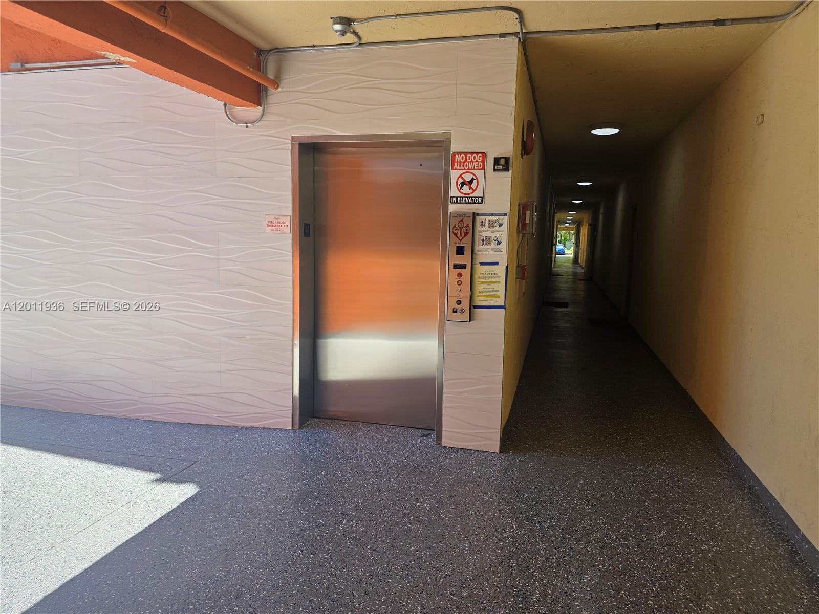 A stainless steel elevator door is located in a hallway with textured wall panels — 8180 Geneva Ct # 322, Doral FL 33166, DORAL, FL