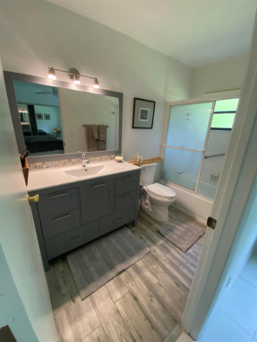 A bathroom features a gray vanity, a large mirror, a toilet, and a shower-tub combo — 5061 Nesting Way # D, Delray Beach FL 33484, DELRAY BEACH, FL