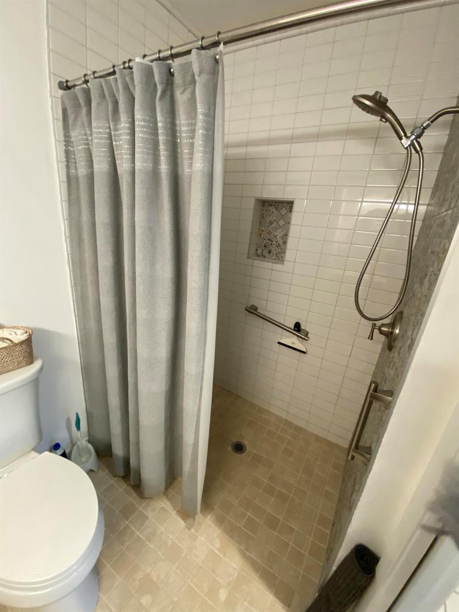 A bathroom features a tiled walk-in shower with a handheld sprayer and a grab bar — 5061 Nesting Way # D, Delray Beach FL 33484, DELRAY BEACH, FL