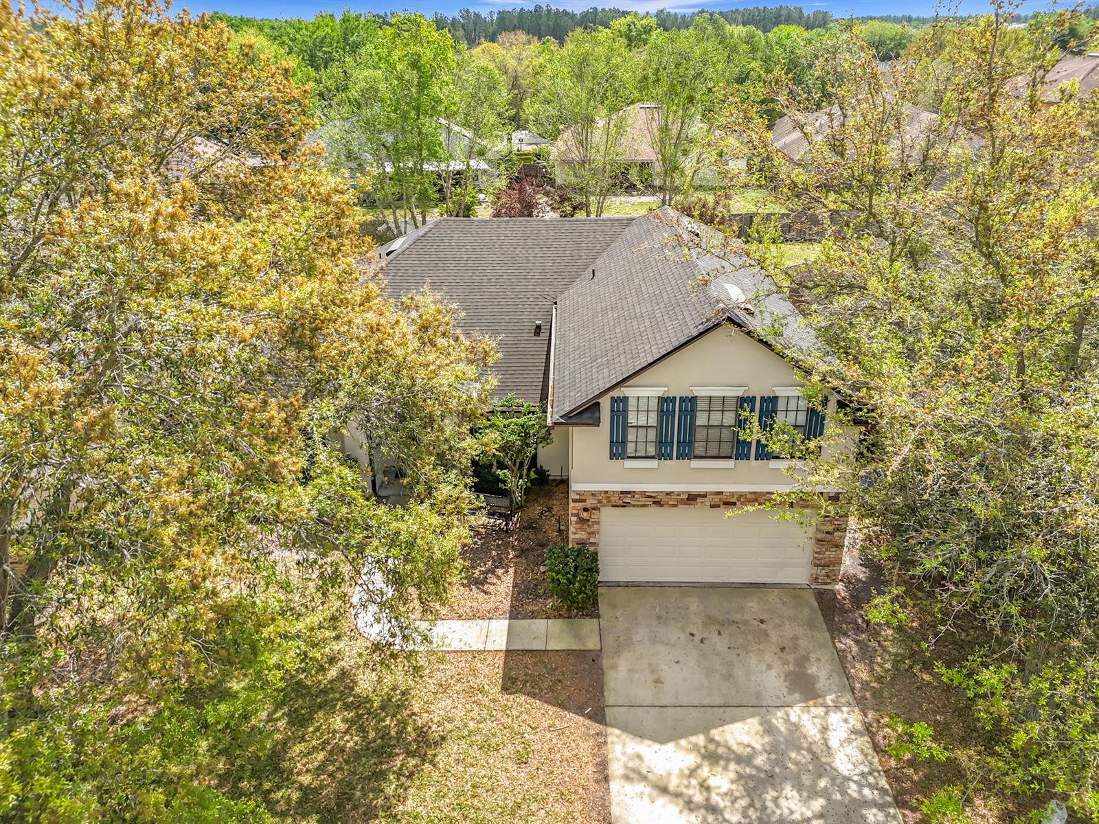 An aerial view of a two-story house with a garage, stone accents, and surrounding trees — 3371 Classic Oak Court, FL 32065, FL