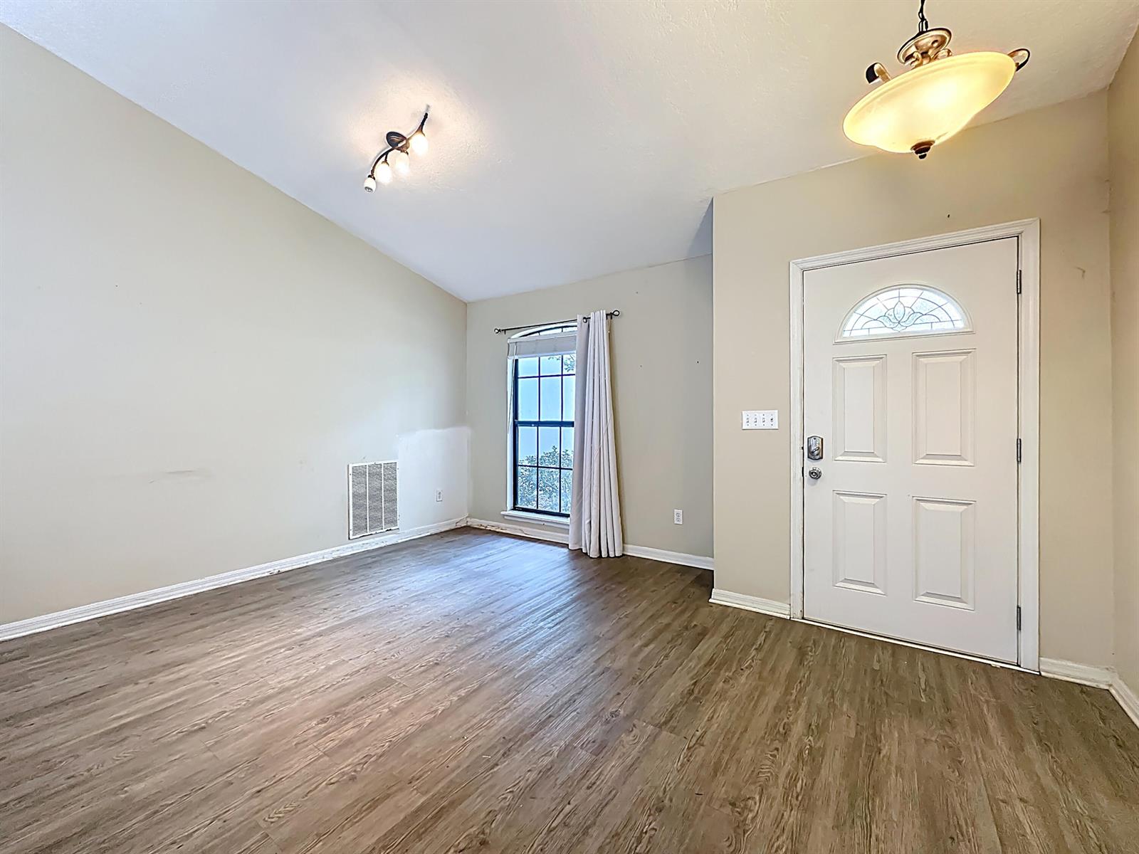 An empty room features light-colored walls, wood-look flooring, a window with curtains, and two light fixtures — 3371 Classic Oak Court, FL 32065, FL