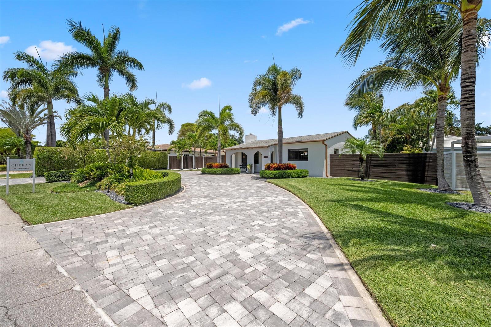 A paved driveway leads to a single-story house surrounded by palm trees and manicured landscaping — 115 Highland Lane, Delray Beach FL 33444, DELRAY BEACH, FL