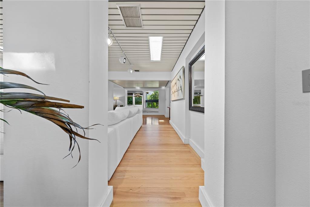 A hallway with light wood flooring leads toward a living area with a white sofa — 932 N HYER AVENUE, ORLANDO, FL