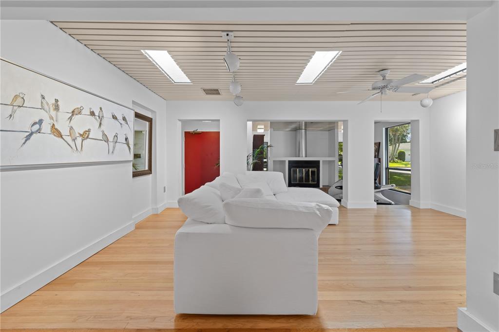 A living room with a white sectional sofa, slatted ceiling, skylights, and a bird-themed wall art — 932 N HYER AVENUE, ORLANDO, FL