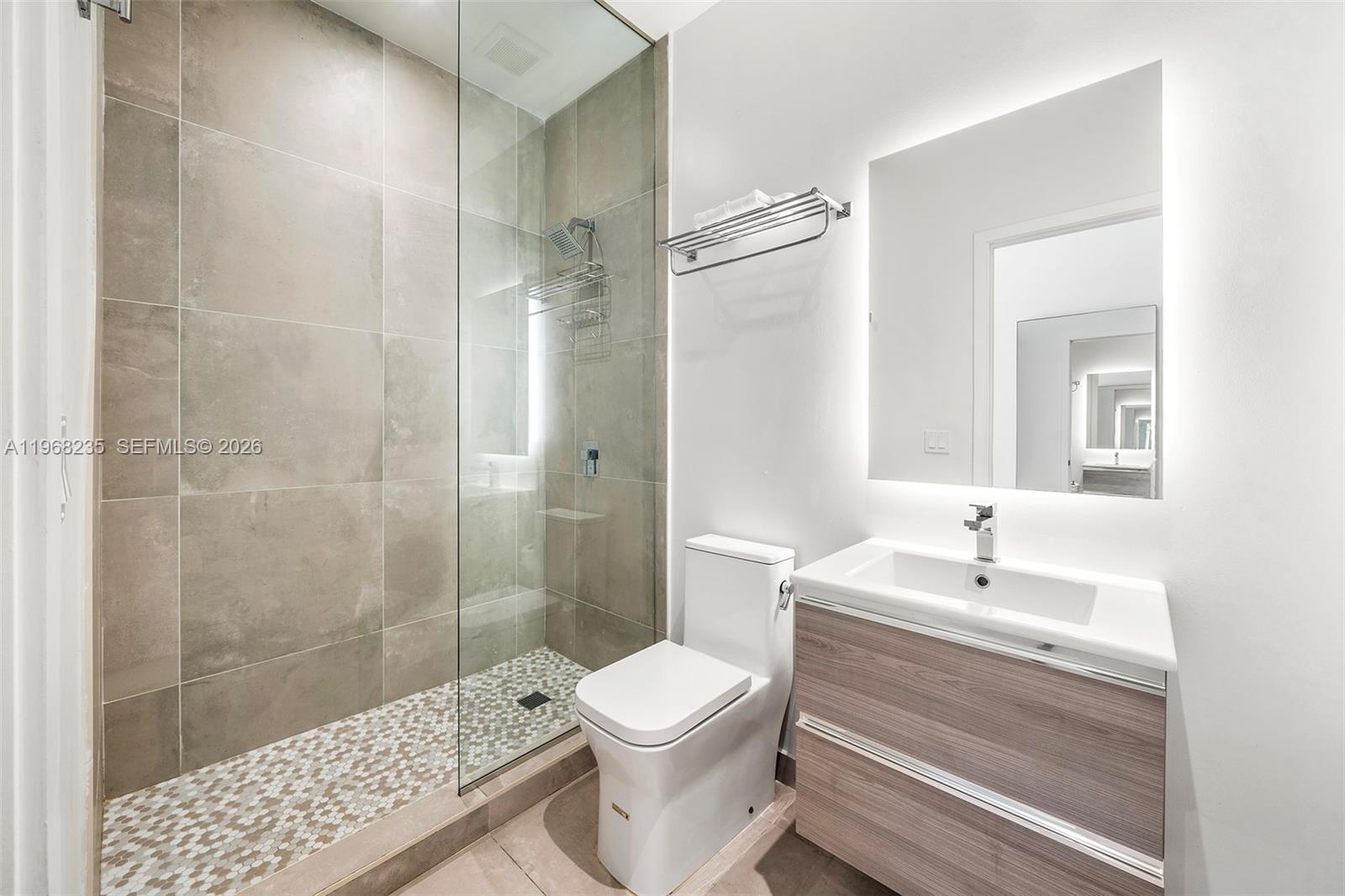 A modern bathroom features a glass-enclosed shower, a white toilet, and a wood-toned vanity — 229 SW 9th St # 208, Miami FL 33130, MIAMI, FL
