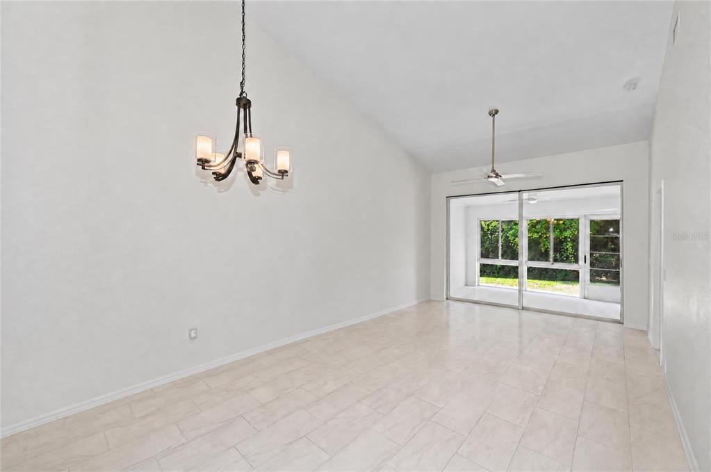 A dining room with a vaulted ceiling, a chandelier, tile flooring, and sliding glass doors — 5623 MONTE ROSSO ROAD, SARASOTA, FL