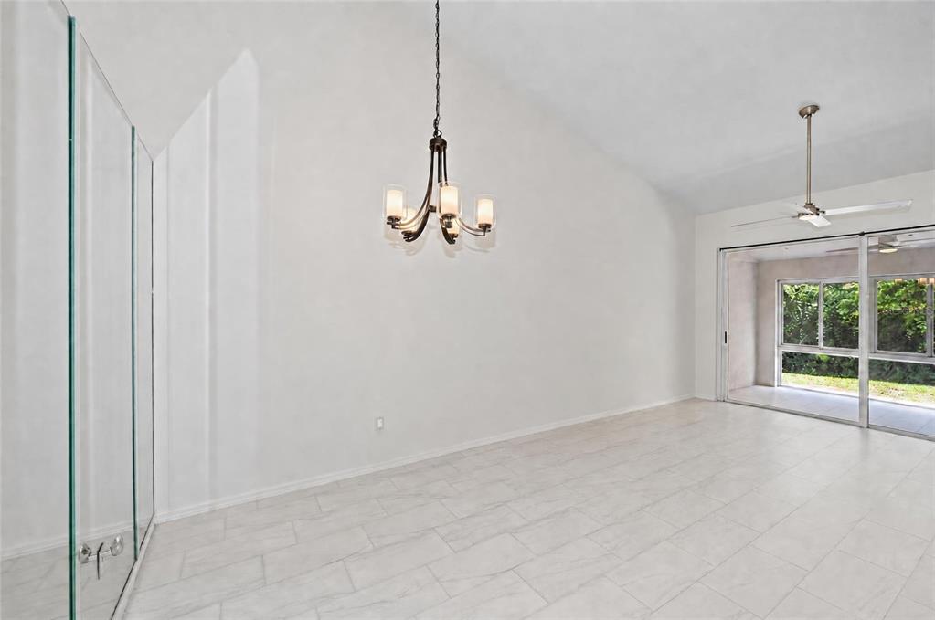 A bright room with white tile floors, a chandelier, and sliding glass doors to a patio — 5623 MONTE ROSSO ROAD, SARASOTA, FL