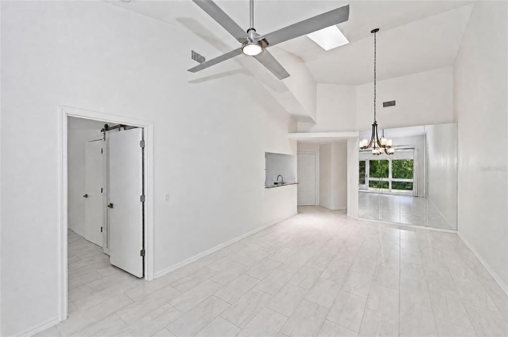 A bright, white-walled room features tile flooring, a ceiling fan, and a mirrored wall — 5623 MONTE ROSSO ROAD, SARASOTA, FL